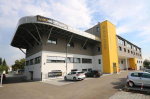 a building with cars parked in a parking lot at Aparthotel AVANGARD Living in Forchheim