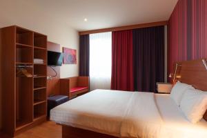 a bedroom with a bed and a dresser at Star G Hotel München Schwabing in Munich