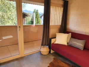 a room with a red couch and a window at Chaletwohnung Dorfbrunnen in Oy-Mittelberg