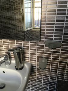 baño con lavabo, espejo y taburete en B&B Luce Viola, en Dorgali