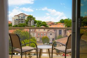 a balcony with chairs and a view of a city at Arc Hôtel Sur Mer in Arcachon