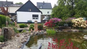 a garden with a pond in front of a house at Ferienwohnung Vergissmeinnicht in Osburg