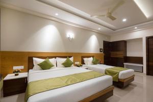a bedroom with two beds and a ceiling fan at Hotel Kheni in Chennai