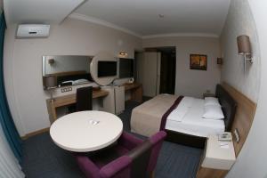 マニサにあるSpilos Hotelのベッド、テーブル、デスクが備わる客室です。