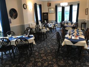 a dining room with tables with blue and white tablecloths at Holly Trees Hotel in Alsager