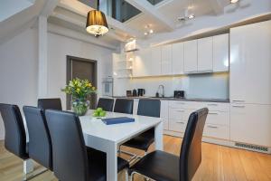 a kitchen and dining room with a white table and chairs at LUXURIOUS APARTMENTS by NOOK NOOK in Krakow
