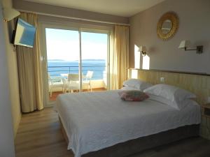 a bedroom with a bed with a view of the ocean at Grand Hotel Moriaz in Le Lavandou