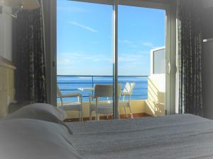 a bedroom with a bed and a view of the ocean at Grand Hotel Moriaz in Le Lavandou