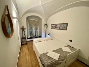 ein weißes Schlafzimmer mit einem Bett und einem Spiegel in der Unterkunft New Apartament in historical Genoa center in Genua