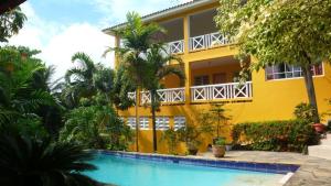 een geel huis met een zwembad ervoor bij Casa Tropical in San Felipe de Puerto Plata