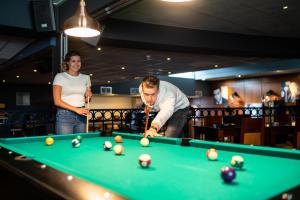 a man and a woman playing a game of pool at Fletcher Wellness-Hotel Brabant-Mill in Mill