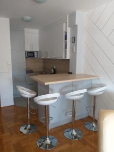 a kitchen with white cabinets and bar stools at Apartman Jelacic Vinkovci in Vinkovci