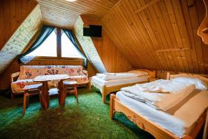 a room with two beds and a table in a attic at Osada na Brzyzku in Poronin