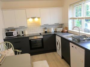 a kitchen with black counters and white cabinets and a sink at Apartment 61 in Wetherby