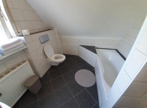 a small bathroom with a toilet and a tub at B&B Die Herrlichkeit in Lage