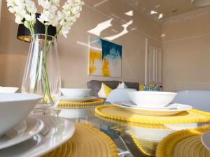 een glazen tafel met witte gerechten en een vaas met bloemen bij Tay View Apartment in Dundee