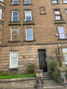 um velho edifício de tijolos com uma porta preta em Tay View Apartment em Dundee