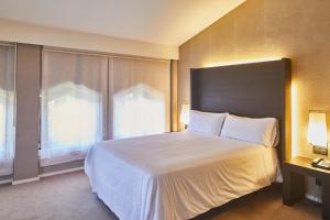 Un dormitorio con una gran cama blanca y una ventana en Silken Gran hotel Durango en Durango