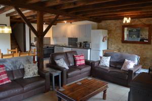 a living room with leather couches and a kitchen at The Railway Cottage - characterful and comfortable holiday cottage in Piégut-Pluviers