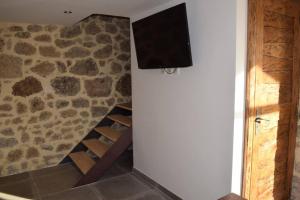 um quarto com uma televisão e uma parede de pedra em Gîte Le Pilat em Vernoux-en-Vivarais