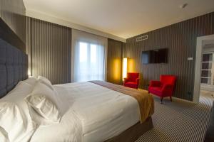 um quarto de hotel com uma cama e duas cadeiras vermelhas em Silken Gran hotel Durango em Durango
