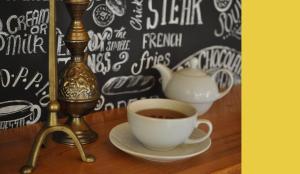 a cup of coffee sitting on a table next to a tea pot at Casa Romaneasca in Curtea de Argeş