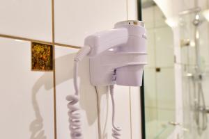 białą suszarkę do włosów w łazience obok lustra w obiekcie Žemyna Apartmentai w Druskienikach