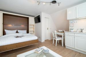 a bedroom with a bed and a desk and a kitchen at Strandläufernest in Tinnum