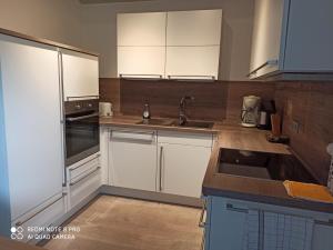 una cocina con armarios blancos y electrodomésticos de acero inoxidable en Der Amboss, en Wangerland