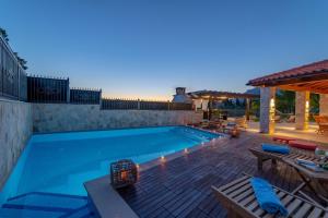 una piscina con terraza y un patio con sillas en Villa San Nicolo, en Gruda