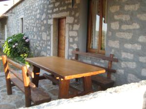 une table en bois et deux bancs à côté d'un bâtiment dans l'établissement Stazzo Fossuli, à Sant Antonio Di Gallura