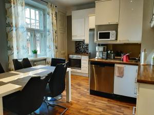 uma cozinha com mesa e cadeiras e uma cozinha com armários brancos em Go Happy Home Vilhonkatu 9. Stylish home in the heart of the city centrer em Helsinque