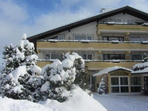 a building with snow covered trees in front of it at Ferienhotel Schwarzwälder Hof in Feldberg