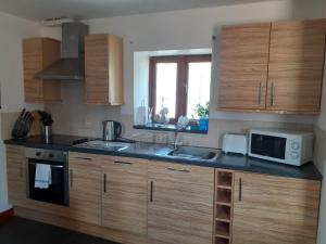 a kitchen with wooden cabinets and a sink and a microwave at The Carthouse in Aberystwyth