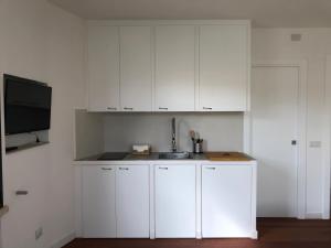 纳尔多Sunny Apartments的一间带白色橱柜和水槽的厨房以及一台电视。 更多16张照片