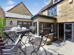 a patio with a table and chairs in front of a house at Browns Cottage in Chipping Norton