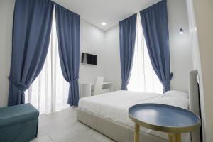 Schlafzimmer mit blauen Vorhängen, einem Bett und einem Tisch in der Unterkunft La Chambre in Neapel