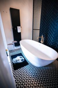 a bathroom with a white tub and a black tile floor at Lit d'Art Exclusive Boutique Hotel in Antwerp
