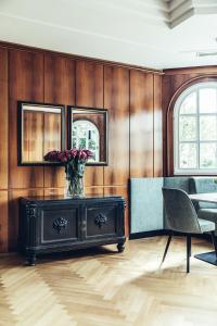 a living room with a table and a vase of flowers at Hotel Dermuth Klagenfurt in Klagenfurt