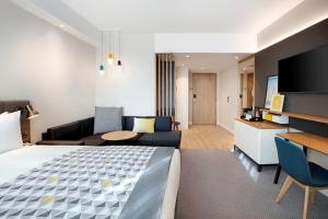 um quarto de hotel com uma cama e uma sala de estar em Holiday Inn London Heathrow - Bath Road, an IHG Hotel em Hillingdon