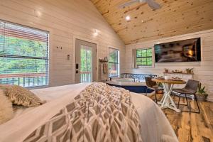 a bedroom with a bed and a table and a tv at Charming Broken Bow Cabin with Jacuzzi and Fire Pit! in Broken Bow