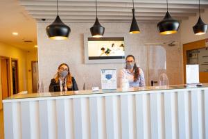 two women wearing face masks sitting at a counter at Park Hotel Porto Aeroporto in Maia