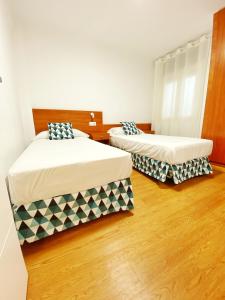 2 Betten in einem Zimmer mit Holzböden in der Unterkunft Primera Linea De Mar Centro Roses in Roses