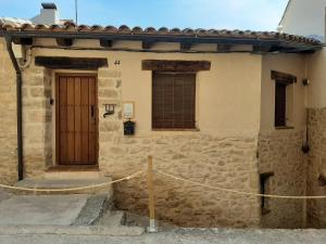 a stone building with a wooden door and a fence at APARTAMENTOS MATARRANYA in Valderrobres