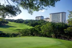 奧斯汀的住宿－Omni Barton Creek Resort and Spa Austin，享有高尔夫球场绿地的景色,建筑背景