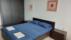 a bedroom with a blue bed with two towels on it at Panorama Apartment & Rooms Veliko Turnovo in Veliko Tŭrnovo