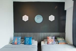 イポーにあるMigliore Homestayのベッド2台(枕付)が備わる客室で、壁に看板が付いています。