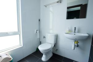 La salle de bains blanche est pourvue de toilettes et d'un lavabo. dans l'établissement Migliore Homestay, à Ipoh