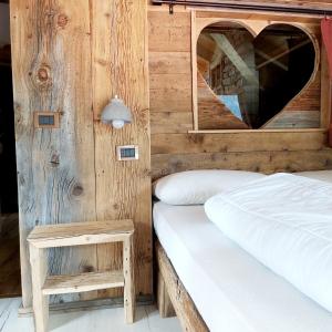 - une chambre avec un lit et un miroir en forme de cœur dans l'établissement La Tana dell'Orso, à Campitello di Fassa