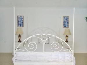 Cama blanca en habitación blanca con 2 lámparas en Ocean Front Property - Villa 4 Aruba w pool view, en Savaneta